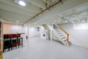A spacious room with a high ceiling, a staircase, and a bar area.