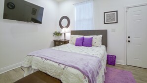 A bedroom with a bed, a bedside table with a lamp, a mirror, a framed motivational quote, and a door. - Stylish Unit 3 Mi to French Quarter & Audubon Park (New Orleans)