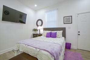 A bedroom with a bed, a bedside table with a lamp, a mirror, a framed motivational quote, and a door. - Stylish Unit 3 Mi to French Quarter & Audubon Park (New Orleans)