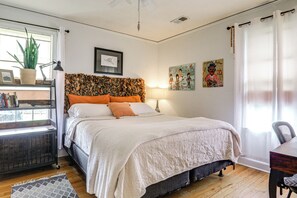 A bedroom with a bed, a bedside table, a chair, a desk, a potted plant, a lamp, and artwork on the wall. - Eclectic Duplex in the Heart of High Point Terrace (Memphis)