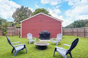 A red shed with a covered grill, surrounded by a grassy yard with four white chairs and a round table. - Eclectic Duplex in the Heart of High Point Terrace (Memphis)
