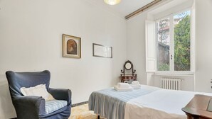 Ein Schlafzimmer mit einem Bett, einem Sessel, einem Heizkörper und einem Fenster mit Blick.