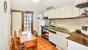 Eine kompakte Küche mit weißen Schränken, einem Holztisch und einem eingebauten Backofen.