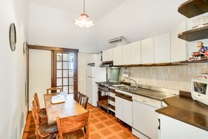 A compact kitchen with white cabinets, a wooden dining table, and a built-in oven. - [VillinoAuroraM] 5TERRE/Near the station (La Spezia)