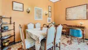 Ein Esszimmer mit Tisch für vier Personen, umgeben von Stühlen, einer Holzkommode mit Geschirr und einer Karte an der Wand.