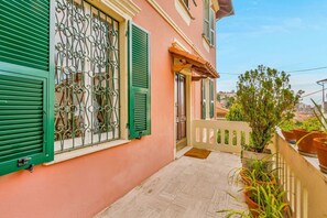 En balkon med gelænder af træ, plantekasser og udsigt over bybilledet.