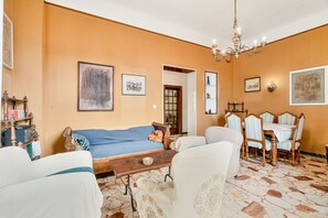 Ein Wohnzimmer mit einer Couch, Stühlen, einem Esstisch und einer Chandelier.