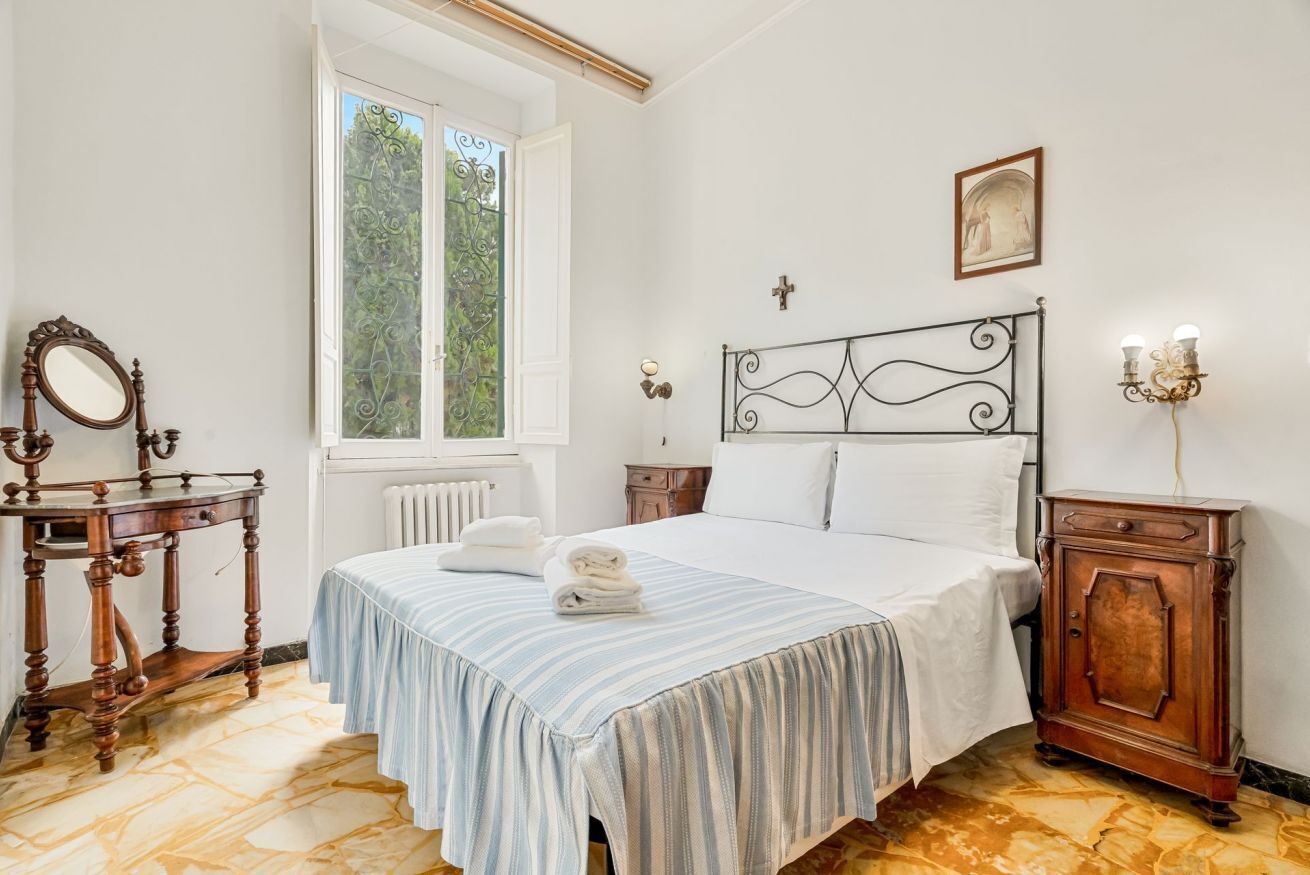 Une chambre à coucher comprenant un lit, une table de chevet, une commode, une fenêtre et un miroir.