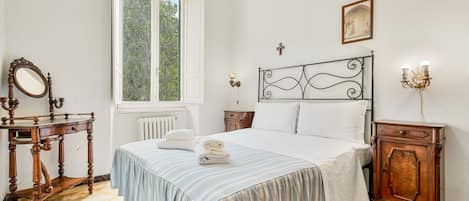 Un dormitorio con cama, mesita de noche, cómoda, ventana y espejo.