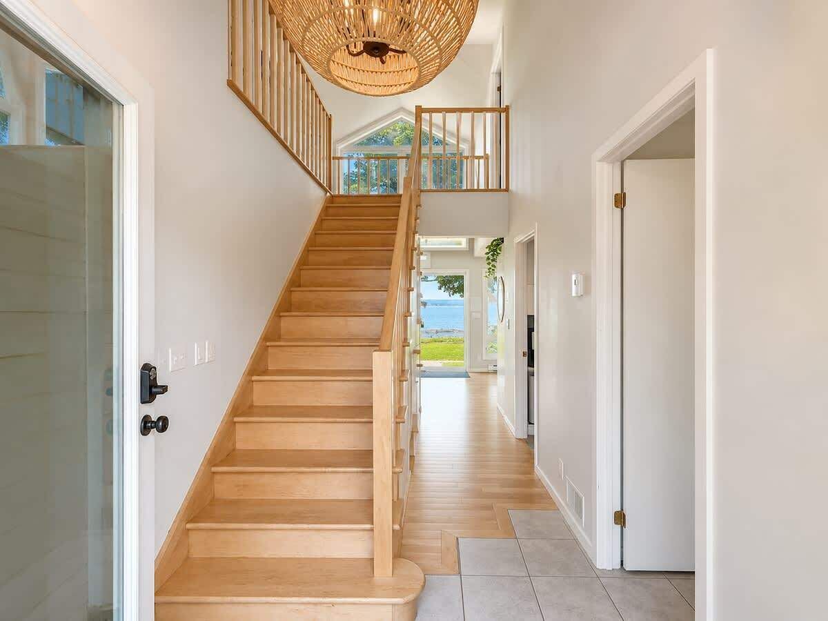 Un escalier en bois menant à un deuxième étage, d’où l’on peut admirer la vue sur l’extérieur.