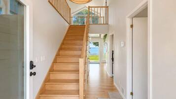 Un escalier en bois menant à un deuxième étage, d’où l’on peut admirer la vue sur l’extérieur.