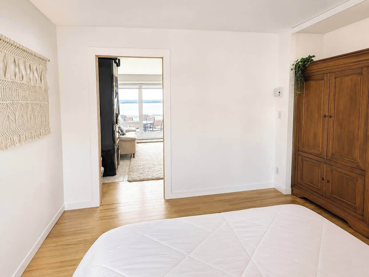 A bedroom with a large bed, wooden wardrobe, and a view to a balcony.
