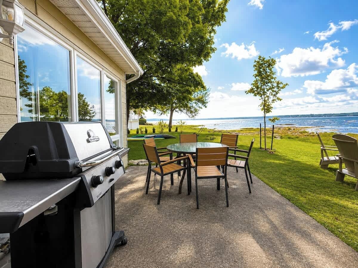 A patio with a grill, a table, and chairs.