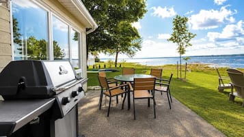 A patio with a grill, a table, and chairs.