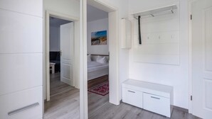 A modern bedroom with a bed, a bedside table, a wardrobe, and a bathroom with a shower. - Villa Marina, Apartment 03, just 450 m from the beach - Dogs Welcome - Modern (Heringsdorf)