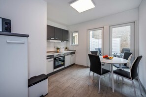 Eine moderne Küche mit Essbereich, ausgestattet mit Backofen, Spüle und Esstisch mit Stühlen.