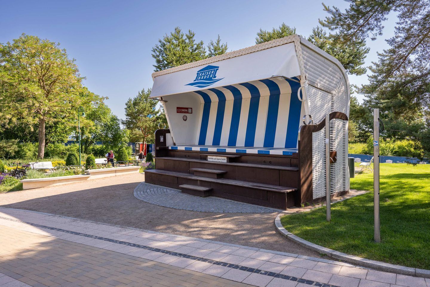 Une caravane immobile, dotée d’une marquise bleue et blanche à rayures, d’un logo et d’une enseigne indiquant qu’il s’agit d’un « foyer permanent ».