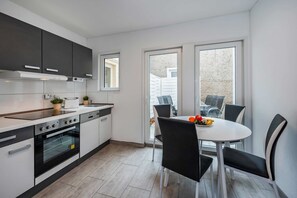 Eine moderne Küche mit Essbereich, ausgestattet mit Backofen, Spüle und einem Esstisch mit Stühlen.