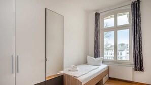 Ein Schlafzimmer mit Bett, Kleiderschrank und einem Fenster mit Vorhängen.