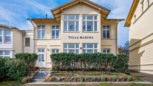 Ein zweistöckiges Gebäude namens 'VILLA MARINA' mit einer symmetrischen Fassade, großen Fenstern und einem zentralen Eingang.