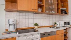 Eine Küche mit Kaffeemaschine, Mikrowelle, Spüle und Schränken.