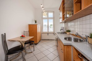 A compact kitchen with a dining table, chairs, a sink, and cabinets. - Villa Marina, Apartment 01, just 450 m from the beach, with a bathtub and shower - Modern (Heringsdorf)