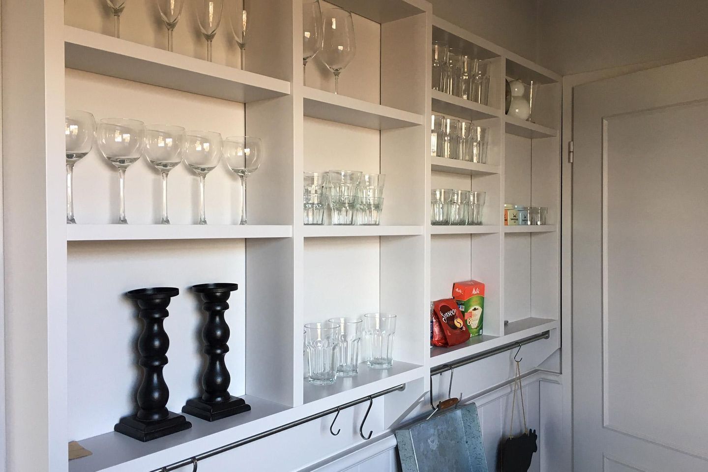 A wine rack with multiple shelves holding wine glasses and bottles.