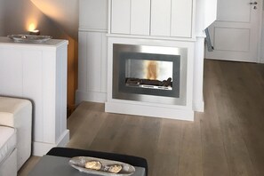 Ein modernes Wohnzimmer mit eingebautem Kamin, weißen Schränken und Holzboden.