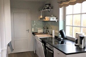 Eine kleine Küche mit Spüle, Herd und einem Fenster für natürliches Licht.