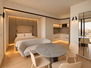 A modern hotel room with a bed, a dining table, and a kitchen area. - 7 R House (Milano)