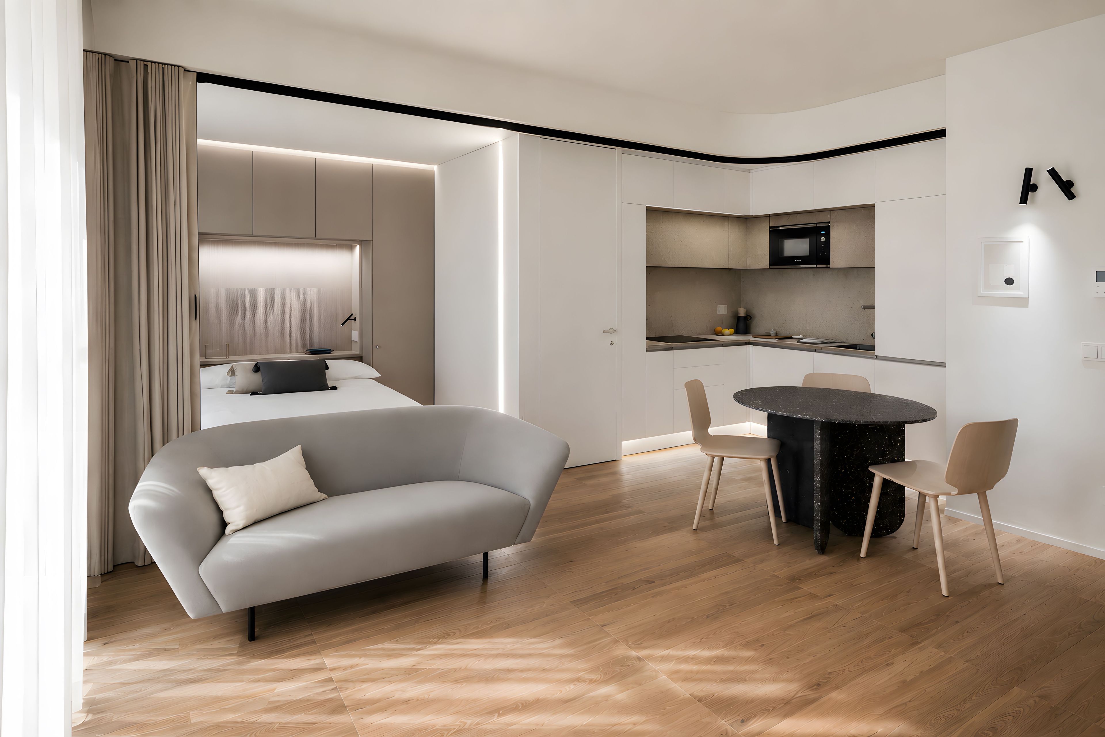 A modern living room with a sofa, a dining table with chairs, a kitchen area with a microwave, and a large window with curtains.