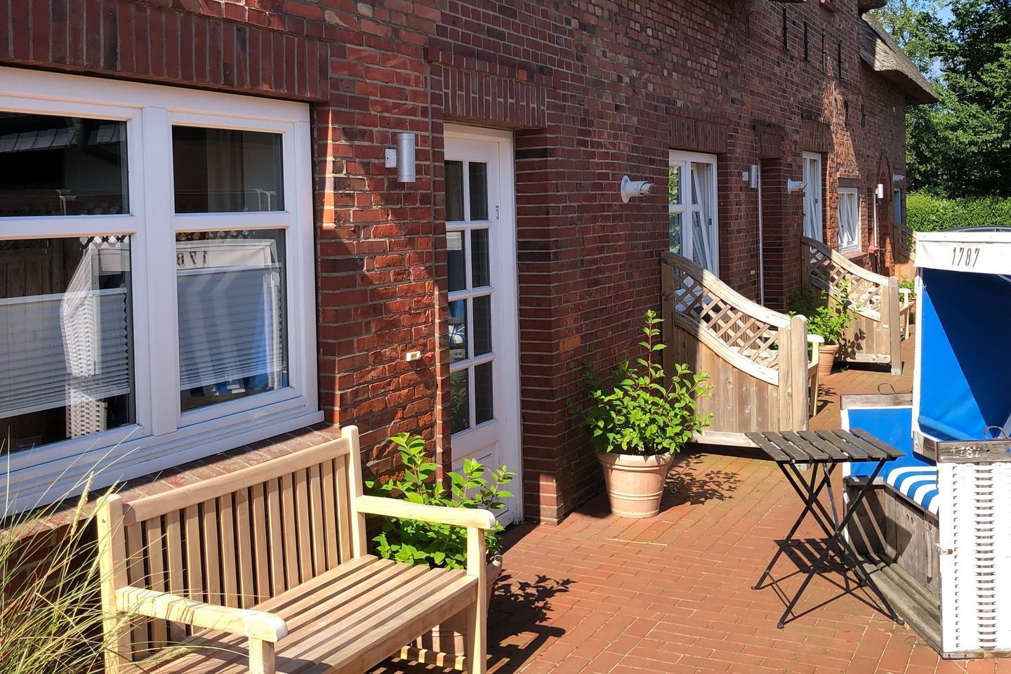 A brick building with a wooden bench, a potted plant, and a blue and white outdoor seating area.