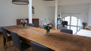 Un'ampia sala da pranzo con un tavolo in legno, sedie e due lampade a sospensione.