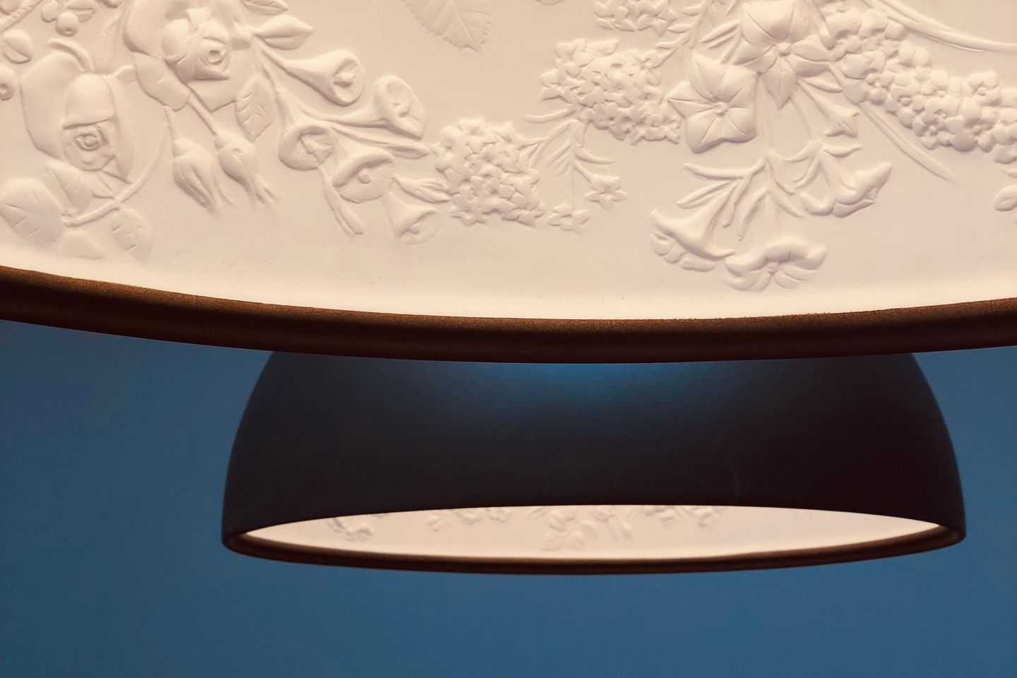 Un plafond orné de motifs floraux et un pied de lampe.