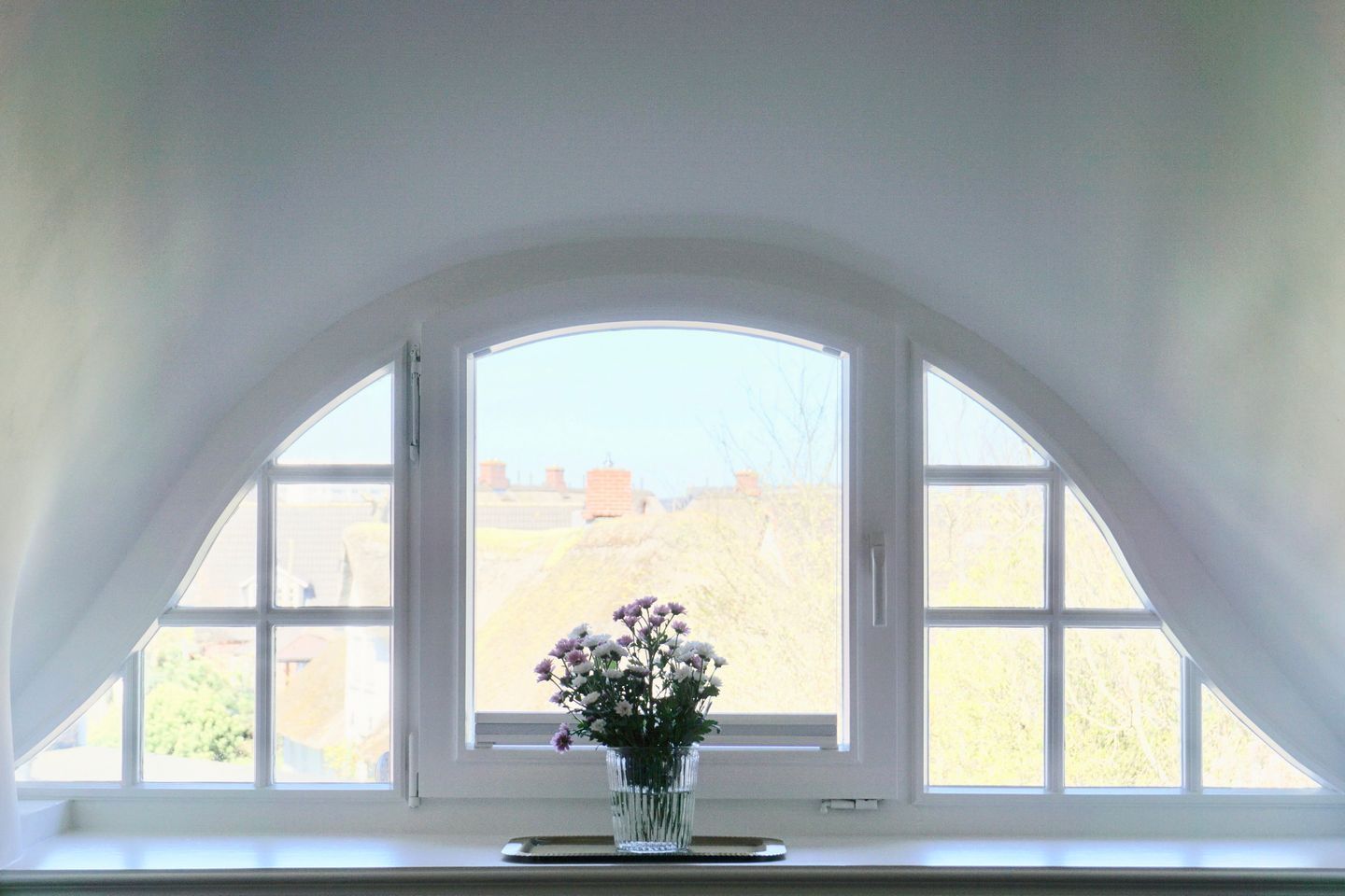 A room with a large arched window overlooking a landscape.