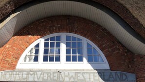 Un edificio in mattoni con una finestra ad arco bianca e un cartello con su scritto 'KONSUMVEREIN WESTERLAND'.