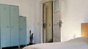 Et soveværelse med seng, skab og en dør til et andet rum.