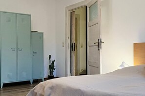 Ein Schlafzimmer mit einem Bett, einem Kleiderschrank und einer Tür zu einem weiteren Raum.
