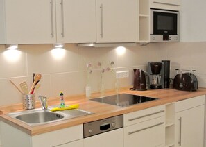 A modern kitchen with stainless steel appliances, a double sink, and a coffee maker. - Alter Konsumverein, App No. 6 - Cozy Apartment at the Alter Konsumverein on (Sylt)