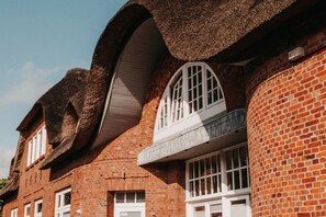 Un bâtiment à la façade en briques, doté de grandes fenêtres en arc de cercle et d’une structure de toit incurvée distinctive.