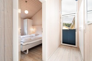 Une chambre à coucher comprenant un lit, une armoire et une porte donnant sur un espace extérieur.