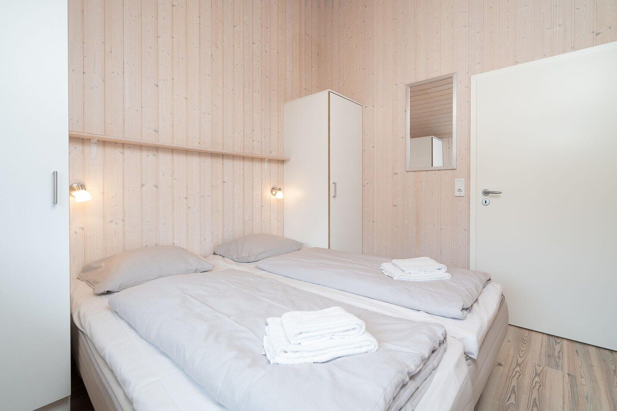 Ein Schlafzimmer mit zwei Betten, einem Kleiderschrank, einem Spiegel und einer Tür.