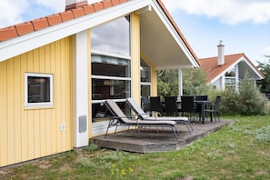 A yellow building with a covered patio area featuring outdoor furniture. - Geräumiges Strandhaus in Grobenbrode (Großenbrode)