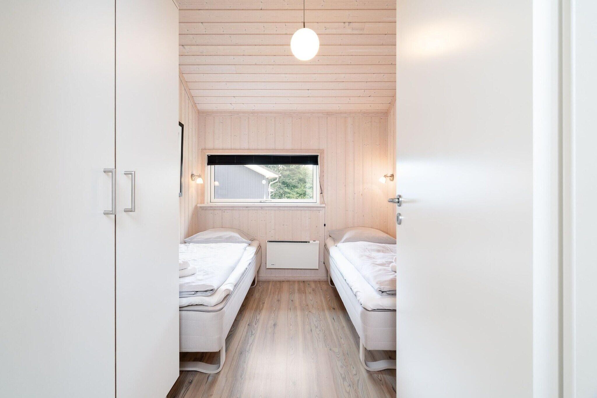 Una habitación con dos camas, una ventana y una lámpara en el techo.