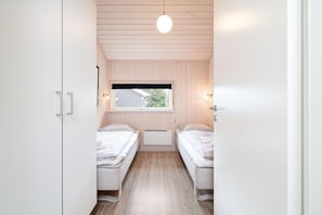 A room with two beds, a window, and a ceiling light. - Geräumiges Strandhaus in Grobenbrode (Großenbrode)