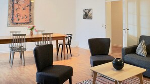 A modern living room with a sofa, chairs, a dining table, and a coffee table. - Alter Konsumverein, App No. 5 — An Oasis of Well-Being: Alter Konsumverein App No. 5 on Sylt (Sylt)