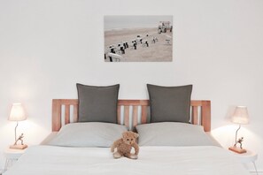 A bedroom with a bed, two pillows, a teddy bear, two bedside lamps, and a wall-mounted picture. - Alter Konsumverein, App No. 5 — An Oasis of Well-Being: Alter Konsumverein App No. 5 on Sylt (Sylt)