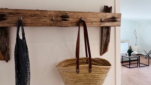 A wooden wall-mounted rack with two bags and a woven basket. - Alter Konsumverein, App No. 2 - Your Comfortable Apartment at Alter Konsumverein (Sylt)