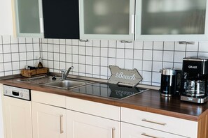 Eine Küche mit modernem Design, ausgestattet mit einem Edelstahlspüle, einer Kaffeemaschine und einem Holunderschild auf der Arbeitsplatte.