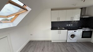 A compact kitchen with a skylight, a washing machine, and a built-in oven. - 2 Min Walk to Tottenham Hotspur Stadium | Bright Studio (London)